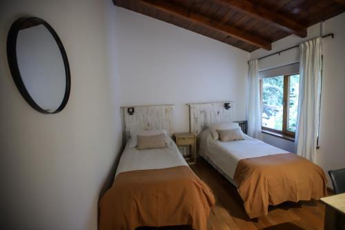 a bedroom with two beds and a mirror at Hostería Carelhue in San Carlos de Bariloche