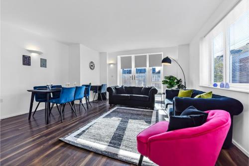 a living room with a pink couch and blue chairs at Charming and Modern 2 BR Flat in London