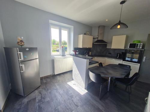 une cuisine avec un réfrigérateur et une table à l'intérieur dans l'établissement Gîte familial et équipé à la campagne avec terrasse, près de Pont-à-Mousson et de nombreuses activités - FR-1-584-73, à Lironville