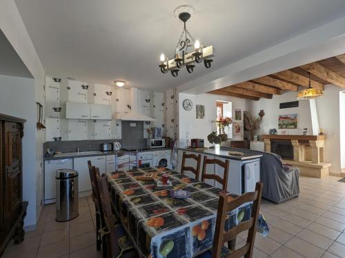 une cuisine avec une table et des chaises et une cuisine avec des placards blancs dans l'établissement Belle maison en pierre au cœur du Berry avec jardin, terrasse, et activités familiales à proximité - FR-1-591-152, à Pérassay