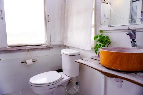 a bathroom with a toilet and a wooden sink at The 99 Cottage (บ้านทุ่งบางปลาม้า) in Suphan Buri