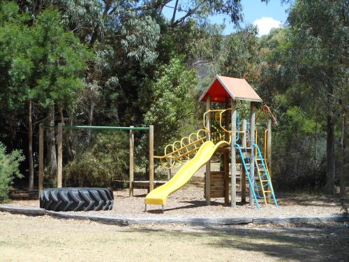 a playground with a yellow slide and a tire at Grampians View Cottages and Units in Halls Gap