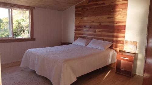 1 dormitorio con 1 cama y pared de madera en Cabaña Frente Al mar, Carretera Austral km 38,6, Puerto Montt, en Puerto Montt