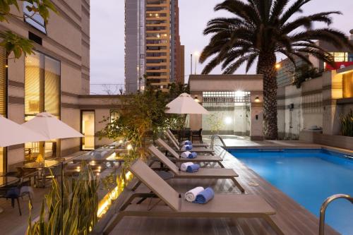 a hotel pool with lounge chairs and a palm tree at Holiday Inn Express - Antofagasta by IHG in Antofagasta