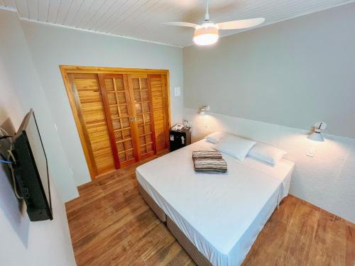 a bedroom with a bed and a flat screen tv at Pousada Ar da Montanha in Serra Negra