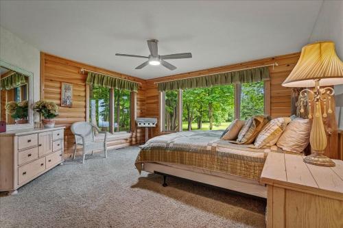 a bedroom with a bed and a desk and windows at Woodhaven On Leech Lake in Cass Lake