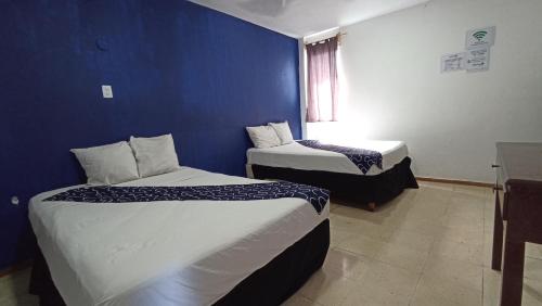 a room with two beds and a blue wall at Hotel Tropical in Progreso