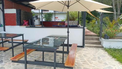 a table and a bench with an umbrella at Finca Maratón Alto in Calarcá
