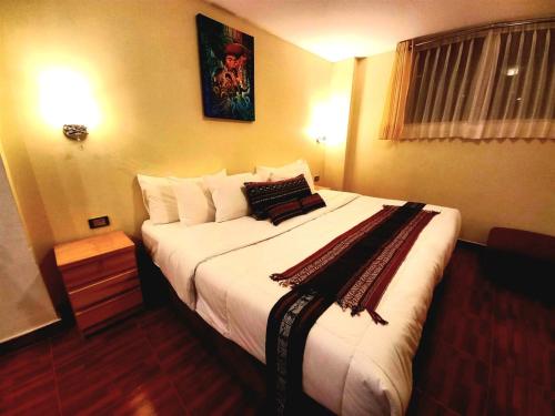 - une chambre dotée d'un grand lit avec des draps et des oreillers blancs dans l'établissement Hotel Humantay Lodge Ollantaytambo, à Ollantaytambo
