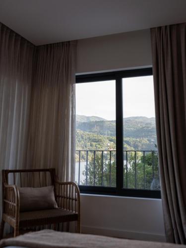 a bedroom with a bed and a window with a view at Quinta da Ribeirinha - Douro River in Paços de Gaiolo