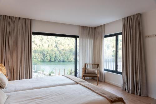 a bedroom with a bed and a large window at Quinta da Ribeirinha - Douro River in Paços de Gaiolo