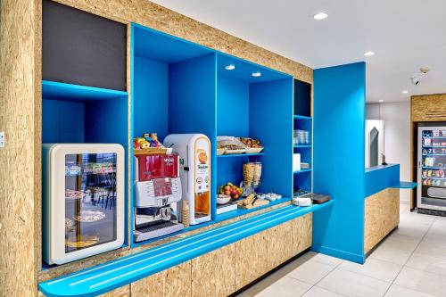a store with blue walls and refrigerators at Kyriad Direct Dijon Sud - Chenove in Chenôve
