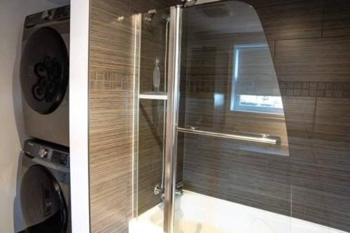 ducha con puerta de cristal y lavadora en Bel appartement au centre-ville, en Granby