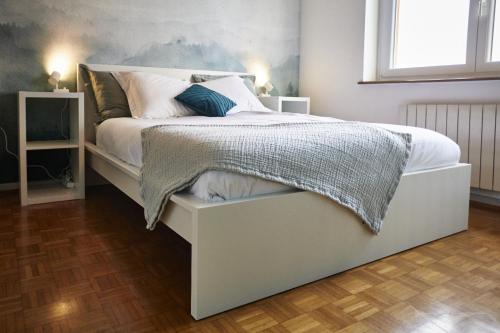 una camera da letto con un grande letto con lenzuola e cuscini bianchi di Maison 140m2 au calme - Beau jardin - à 15mn à pied du Centre-ville de COLMAR a Colmar