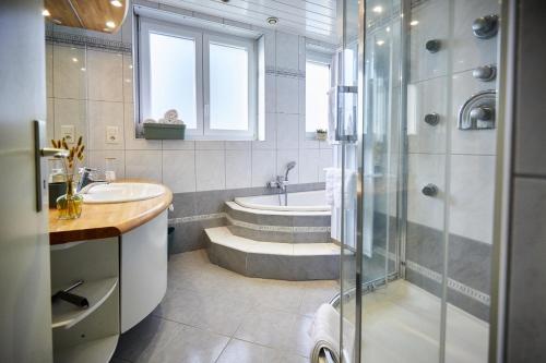 La salle de bains est pourvue d'une baignoire, d'un lavabo et d'une douche. dans l'établissement Maison 140m2 au calme - Beau jardin - à 15mn à pied du Centre-ville de COLMAR, à Colmar