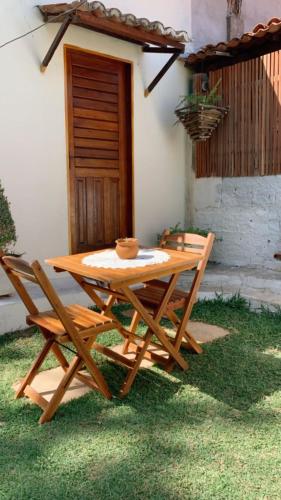 フレシェイラスにあるSuíte Nativa - Flecheirasの木製のピクニックテーブルと家の前の椅子2脚