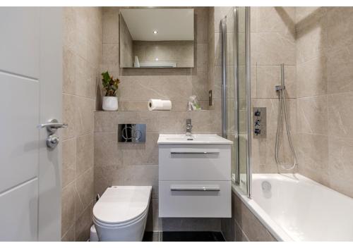a bathroom with a toilet and a sink and a shower at Simply Perfect 2BR 2BT Apartment in London