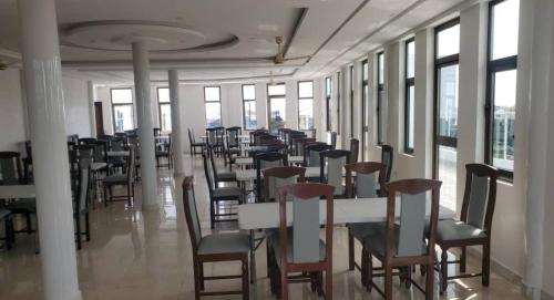 una fila de mesas y sillas en una habitación con ventanas en DIVINE GRACE RESIDENCE INN, en Agblangandan