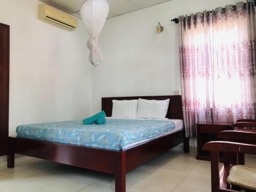 a bedroom with a bed with blue sheets and a window at Nhat Quang Bungalow in Mui Ne