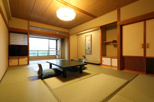 a living room with a table and a large window at Tateyama Prince Hotel in Omachi