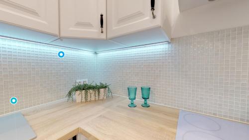 eine Küche mit weiß gefliesten Wänden und zwei blauen Gläsern in der Unterkunft Lillu Apartament 2 in Bydgoszcz