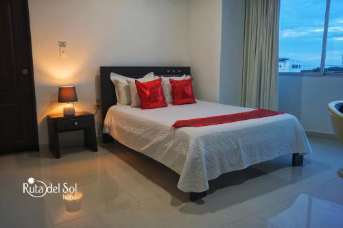 Un dormitorio con una cama con almohadas rojas y una ventana en HOTEL RUTA DEL SOL en Barrancabermeja