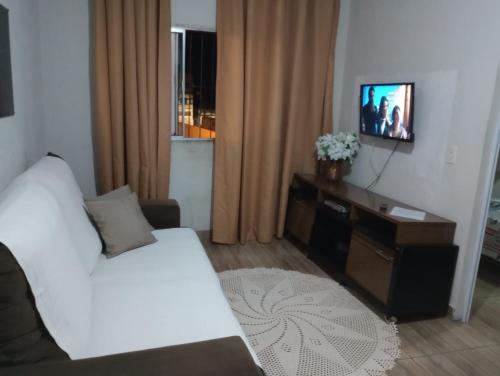 a living room with a white bed and a television at Casa Para Temporada - Cantinho da Cida in Serra