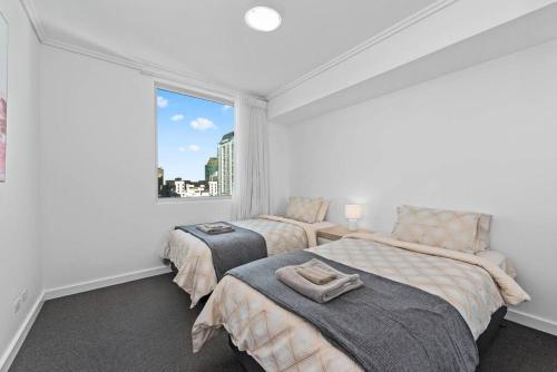 two beds in a room with a window at City Heights! 2Bed/1Bath/1Car/Views ~ CBD in Brisbane