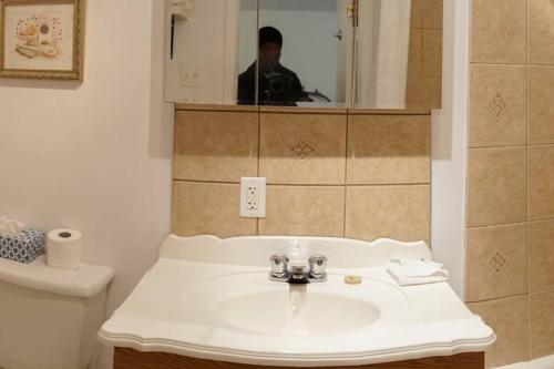a bathroom with a sink and a man in the mirror at 306 Élégance pour les voyageurs in Trois-Rivières