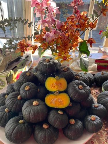 a pile of pumpkins on a table with a vase with flowers at Nantou Fruit House in Renai