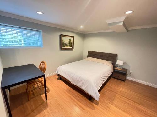 1 dormitorio con cama, mesa y escritorio en Arbutus violet room, en Vancouver