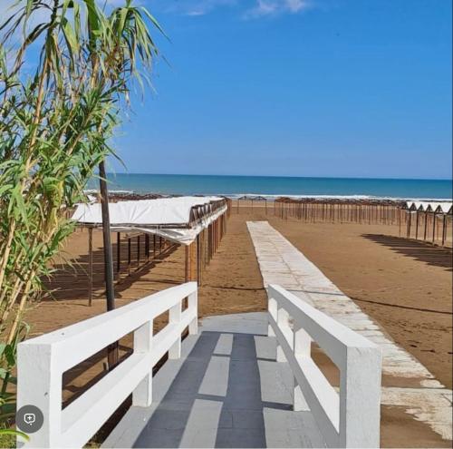 a beach with white benches and the ocean at Duplex del Parque y Balneario in Necochea