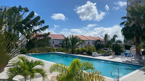 a swimming pool with palm trees and buildings at Magnifique aux Caraibes residence Tradewinds in Cupecoy