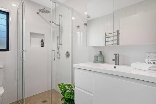 La salle de bains blanche est pourvue d'une douche et d'un lavabo. dans l'établissement Sunrise Reef 6, à Lennox Head