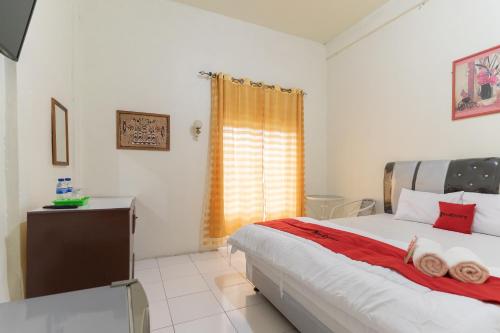 een slaapkamer met een groot bed en een raam bij RedDoorz Syariah @ Jalan Jendral Sudirman Jambi in Palmerah