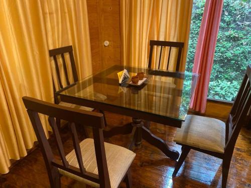 szklany stół z 2 krzesłami i pudełko na nim w obiekcie TREKKING TRAILS ECO STAY w mieście Kalpatta
