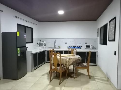 eine Küche mit einem Tisch und Stühlen sowie einem Kühlschrank in der Unterkunft Mirada al Cerro, Apartamento completo in Grecia