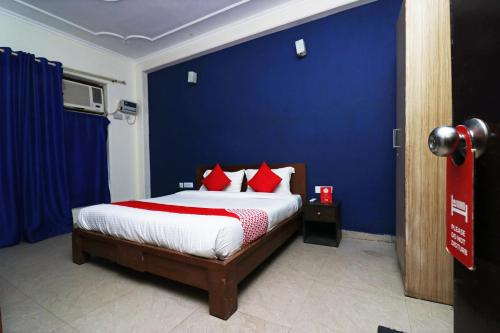 a blue bedroom with a bed with red pillows at OYO Hotel Grand Casa Near Aravali Biodiversity Park in Gurgaon