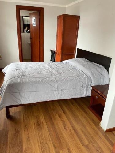 1 dormitorio con 1 cama y suelo de madera en Hotel Hispano, en Cajamarca