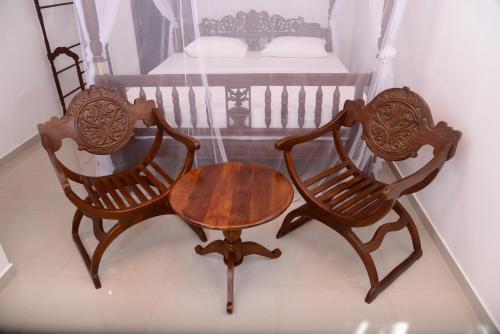 two chairs and a table in a room with a bed at Aayu's Guest in Bentota