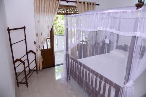 1 dormitorio con cama con dosel y ventana en Aayu's Guest, en Bentota
