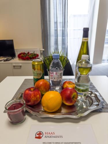 a tray of apples oranges and bottles on a table at Haas Apartments Downtown with Parking in Brno