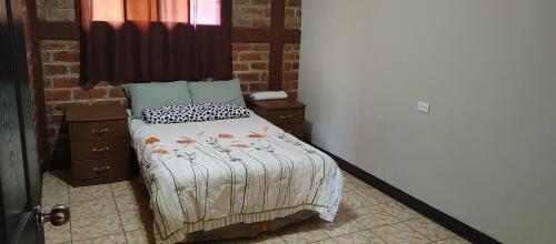 um quarto com uma cama com uma colcha e almofadas em Apartamento Concepción de Ataco, Los Tablones em Ahuachapán