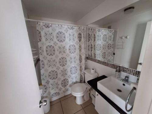 a bathroom with a white toilet and a sink at Excelente depto equipado completo, a pasos del mar in La Serena