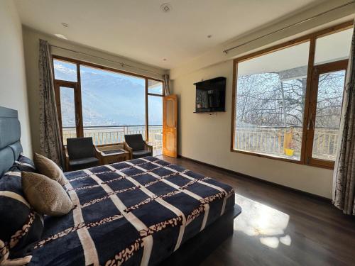 a bedroom with a bed and two windows and a balcony at Nomad Bed & Breakfast in Manāli