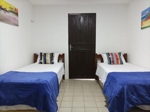 two beds in a room with blue sheets at Casa Encanto da Barra in Fortim