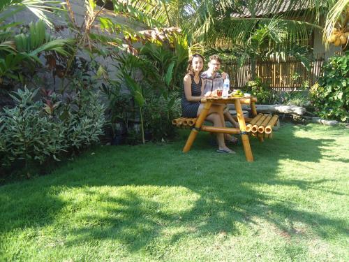 Un uomo e una donna seduti a un tavolo da picnic di Toke Menjangan a Banyuwedang