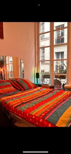 - un lit avec une couverture colorée dans l'établissement Magnifique studio au coeur du Marais, à Paris