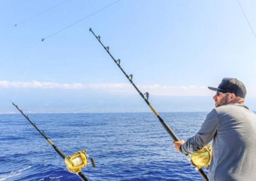 a man standing on a boat with a fishing rod at SUITE 2A, BLUE PAVILION - Steps to BEACH in West Bay