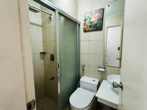 een badkamer met een toilet, een wastafel en een douche bij Birch Tower a1 front of RobinsonMla Rizal Park in Manilla